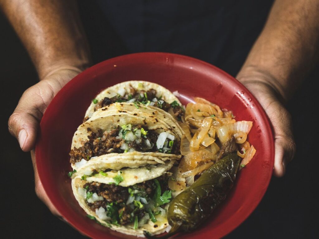 man serving birria tacos in plate