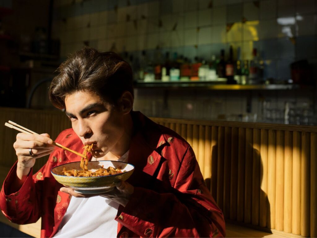 man eating food with chopsticks