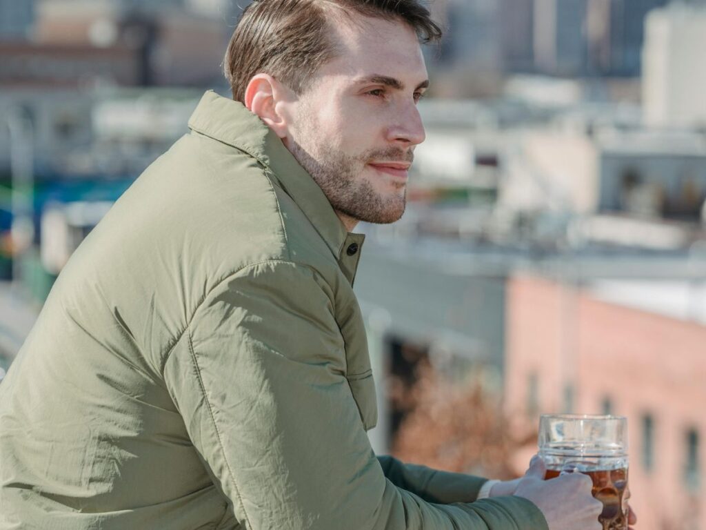 man holding beer on a rooftop bar