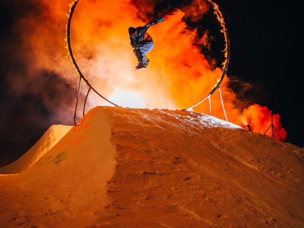 man snowboarding through ring of fire