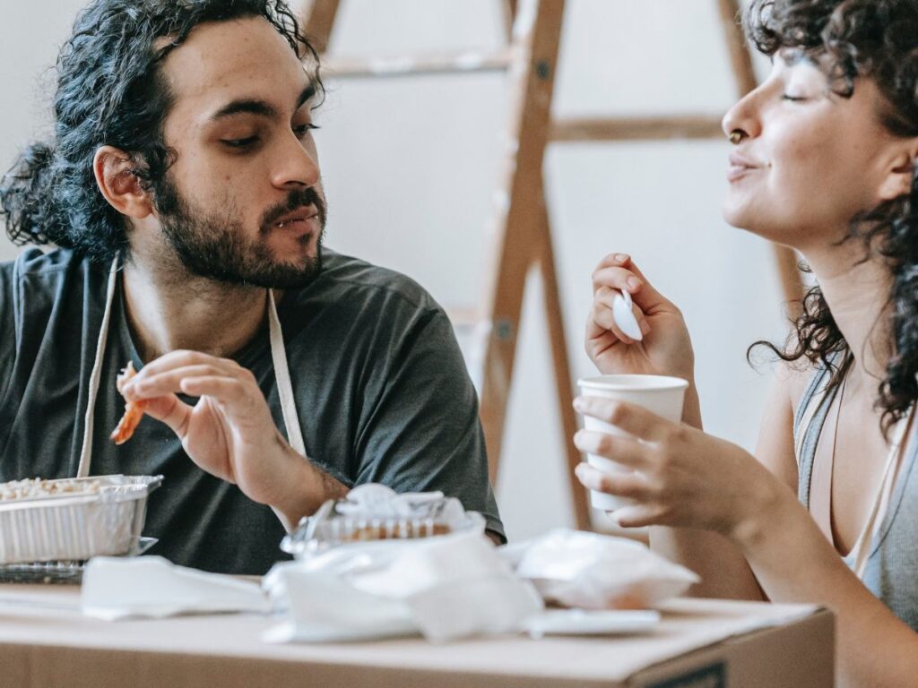 man and woman eating food out of boxes