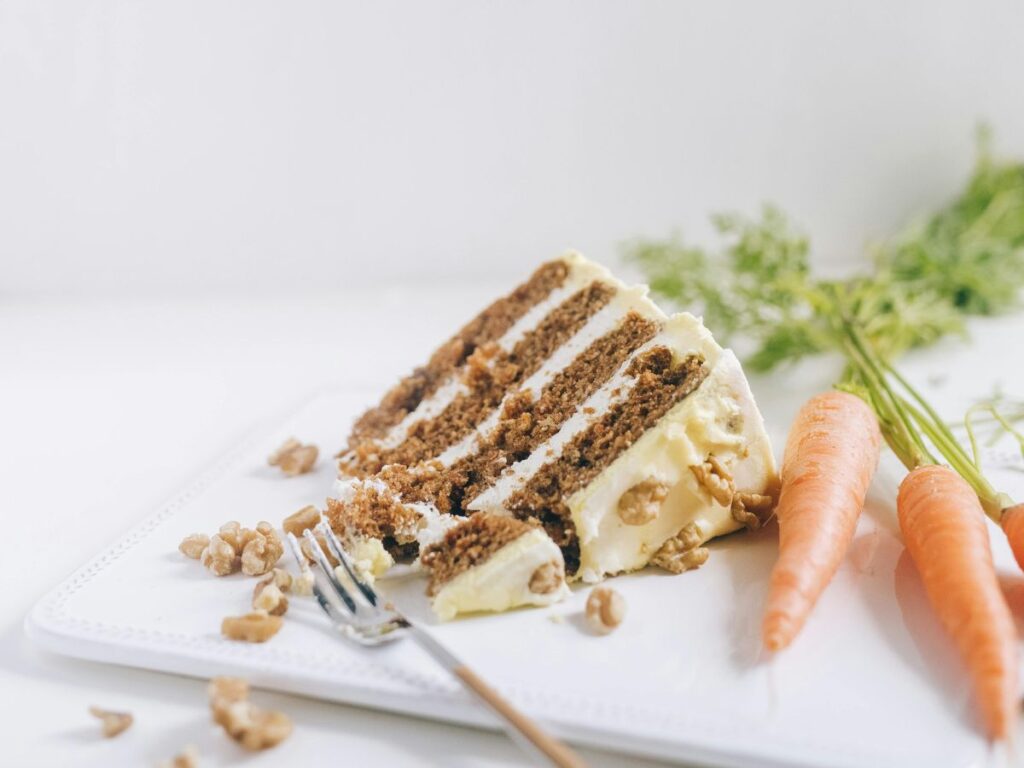 slice of carrot cake with carrot on side