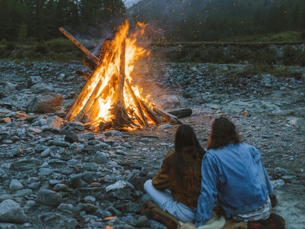 couple sitting beside a camp fire