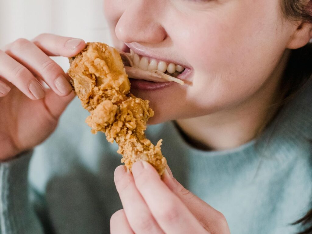 girl eating fried chicken wing