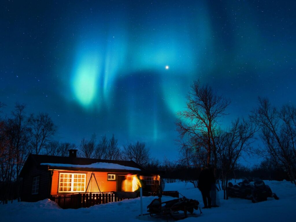 Northern Lights in snow above cabin