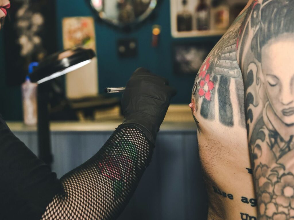 woman making tattoo on a man's chest