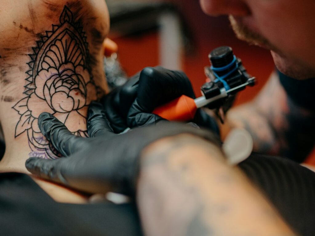 man getting a tattoo on his neck