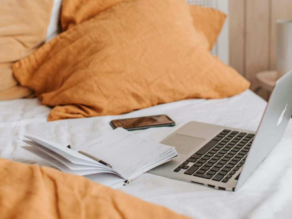 laptop and papers on bed