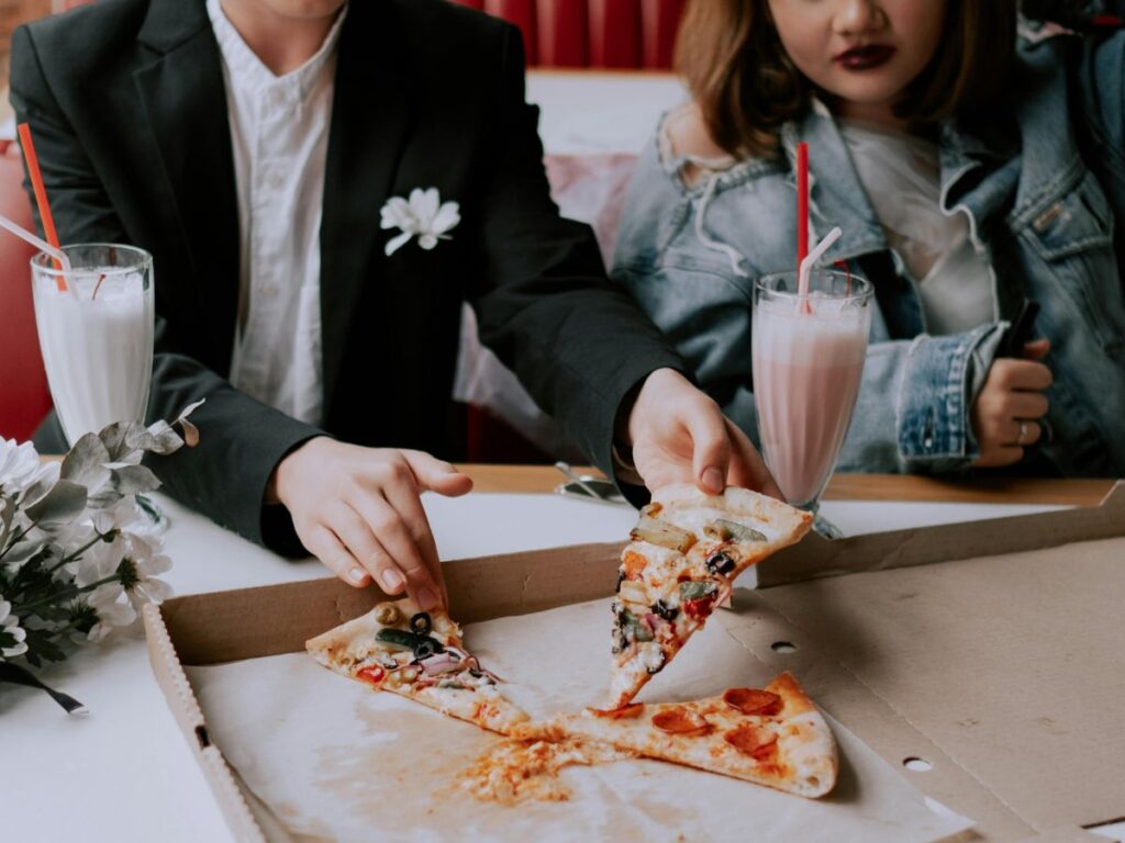 couple eating pizza and shakes in a cafe