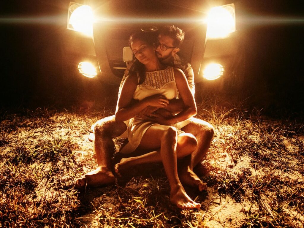 couple sitting in an open area in front of car