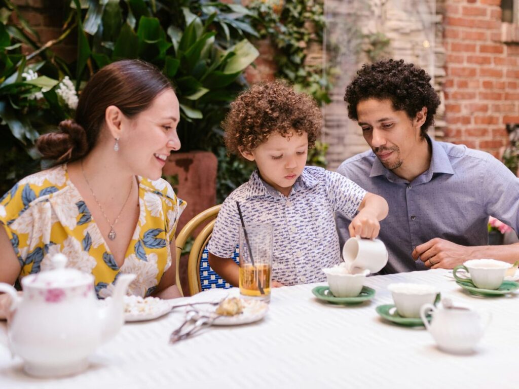 kid pouring tea with his family in a restaurant