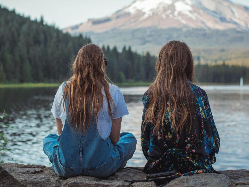 girls by the lake looking at mountains