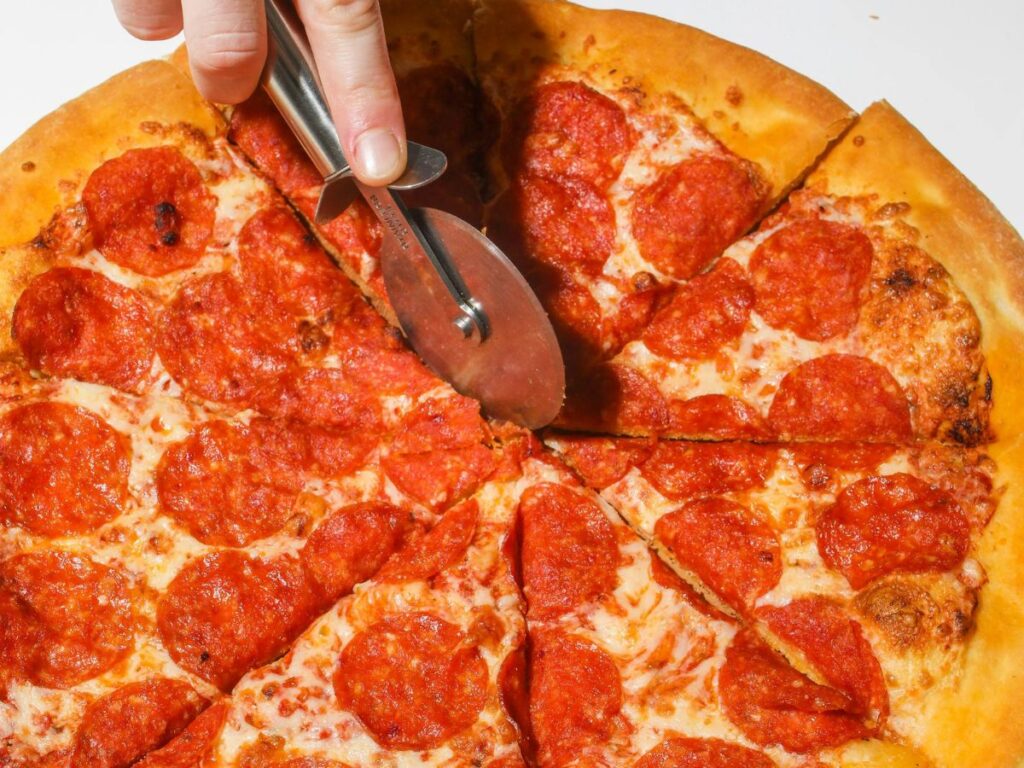 cutting a pepperoni pizza into slices