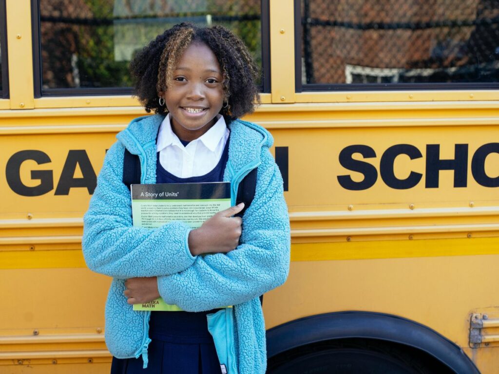 child standing in front of school bus