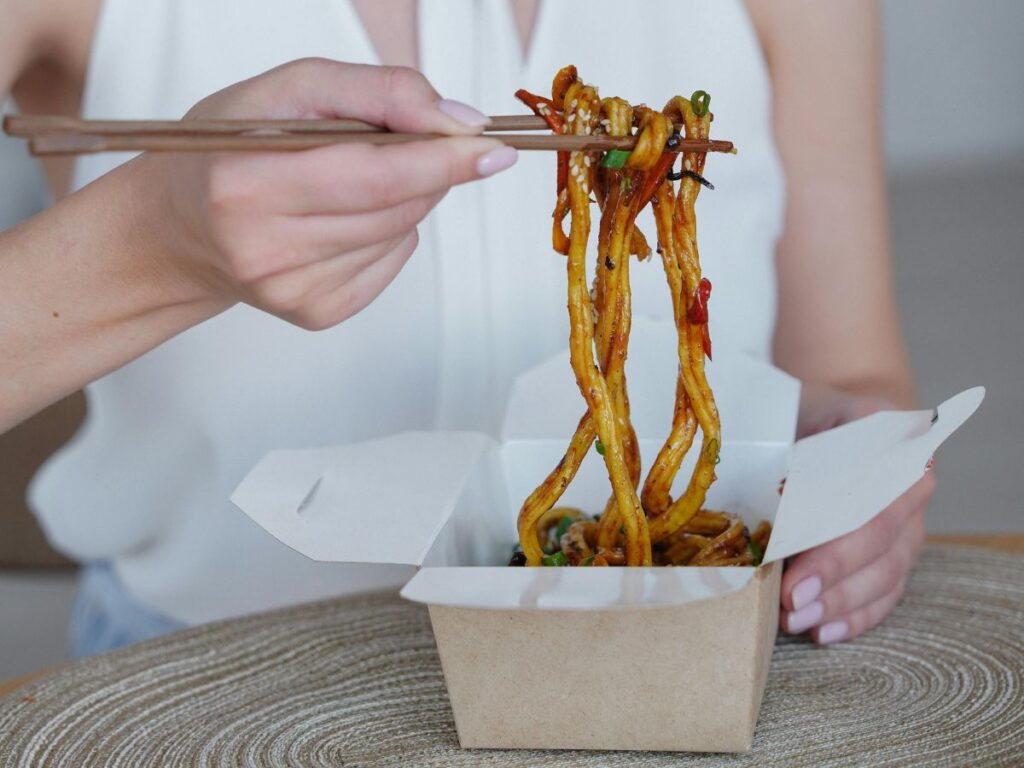 eating noodles in takeout box