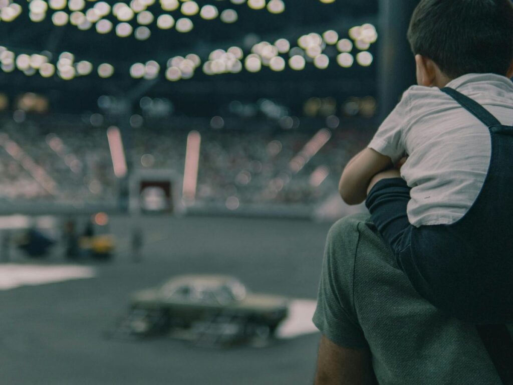 kid watching a game on his father's shoulders