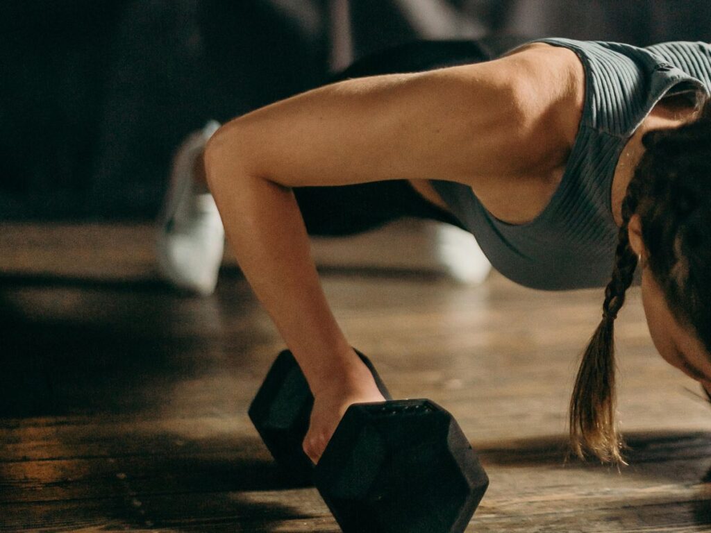 man doing pushups with dumb bell 