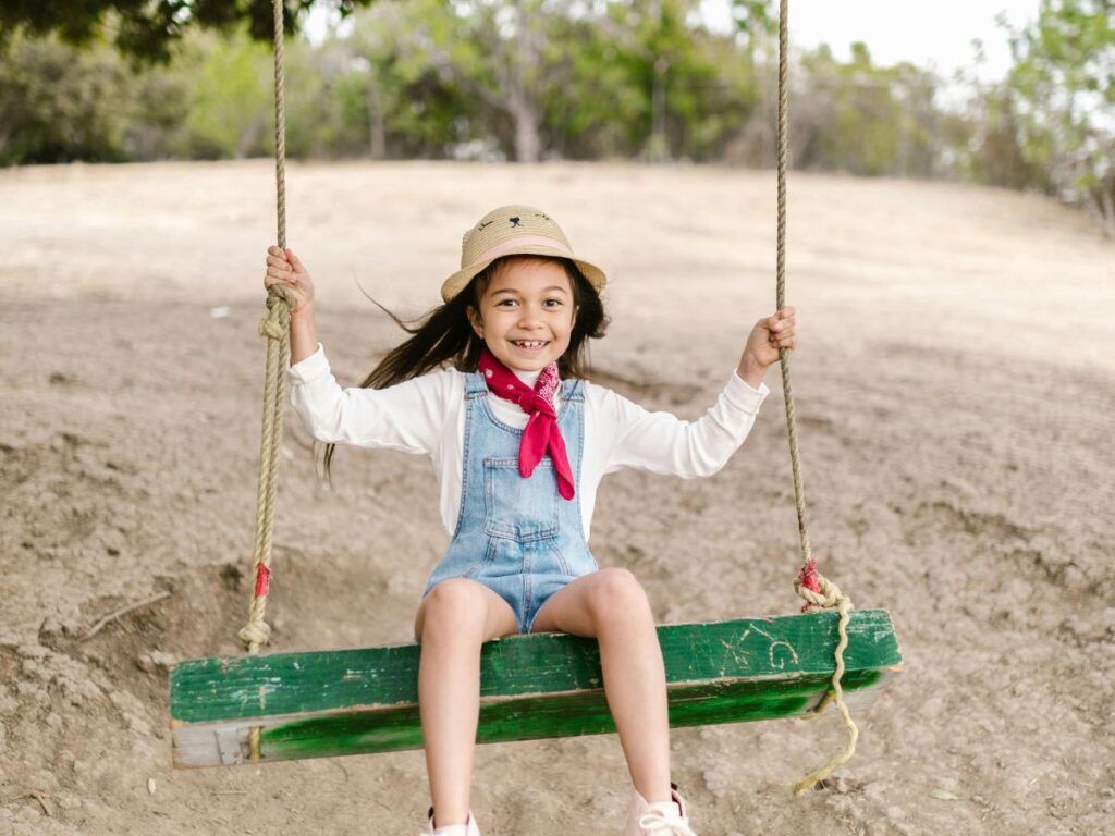 young kid taking swing in a park