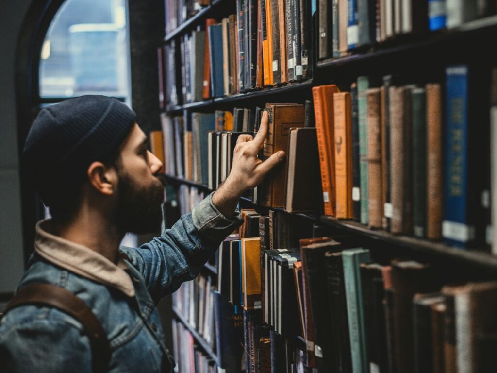 man taking out book in a library